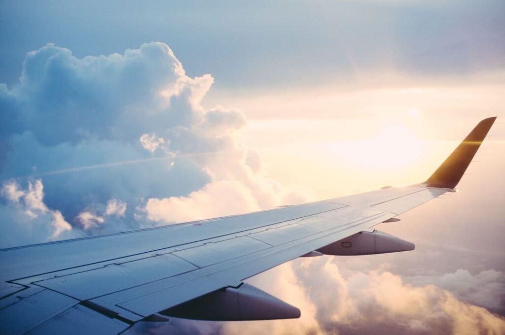 Ausblick aus dem Flugzeugfenster auf den Flugzeugsflügel, Wolken und Sonne
