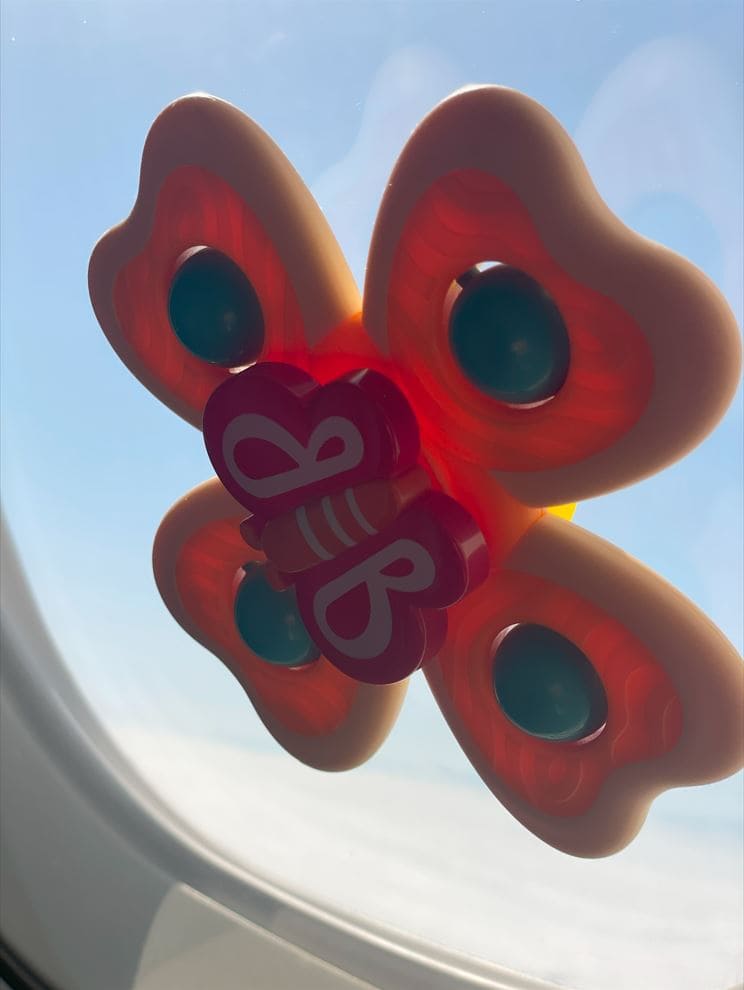 Gelb rotes sich drehendes Spielzeug ist an Flugzeugfenster